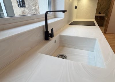 Fehér Corian mosdópult integrált mosdómedencével és fekete csapteleppel