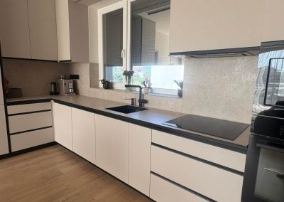 Modern sarokkonyha világos frontokkal és fekete munkapulttal